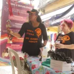 Duas mulheres com uniformes da Camtra entregam rosas para mulheres na Saara